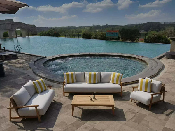 Bahama Outdoor Lounge Set by poolside, teak frame, white cushions, striped pillows.