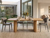 Ashford Dining Table with a natural honey-toned wood top and paired cylindrical pillar legs, displaying visible grain and rounded edges.
