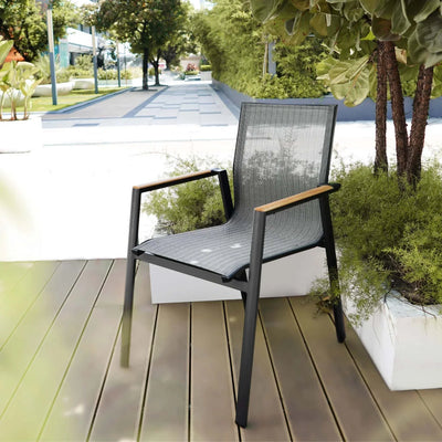 Aspen Outdoor Arm Dining Chair with aluminum frame, charcoal color, and teak slats, placed in a garden setting.