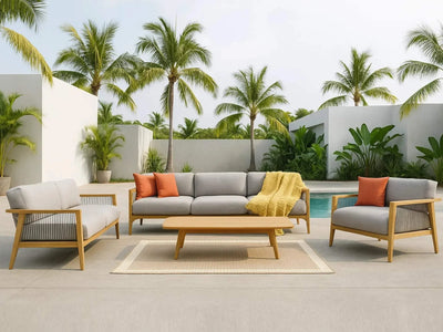 Tribu Outdoor Lounge featuring a 2 seater teak and rope framed outdoor sofa with grey cushions and orange pillows by a pool with palm trees.