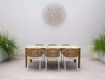 Bella Outdoor Ceramic Dining Table with teak legs in a stylish outdoor setting.