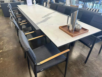 Bonigen Outdoor Dining Chair with teak armrests and aluminum frame at dining table.
