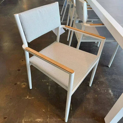 Bonigen Outdoor Dining Chair with teak armrests and aluminum frame in a coastal setting.