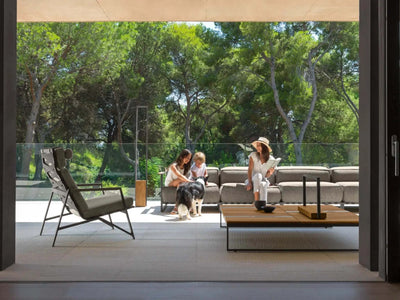 Casilda Outdoor Corner Lounge with neutral cushions and wooden accents on a modern patio with people and a dog outdoors