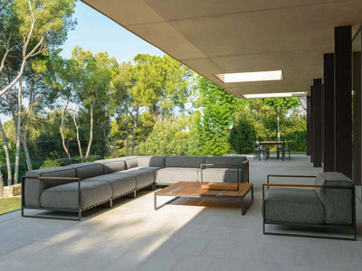 Modern Casilda Outdoor Corner Lounge with neutral cushions and wooden accents on a covered patio surrounded by greenery