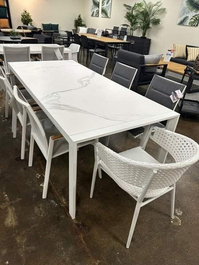 Cebu Outdoor Ceramic Dining Table with white aluminum frame in showroom setting.