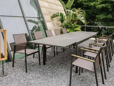 Cebu Outdoor Ceramic Extendable Dining Table on patio with chairs, surrounded by greenery.