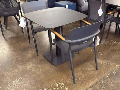 Coco Outdoor Dining Chair with aluminium frame and teak armrest trims in a modern outdoor setting.
