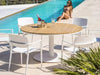 Coco Outdoor Dining Chair by the pool with a round wooden table and a relaxing atmosphere.