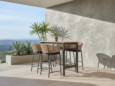 Como Outdoor Wicker Bar Chair with charcoal aluminium frame and natte sooty fabric in outdoor setting