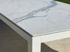 Dante Outdoor Ceramic Dining Table with charcoal frame and marble ceramic top on patio