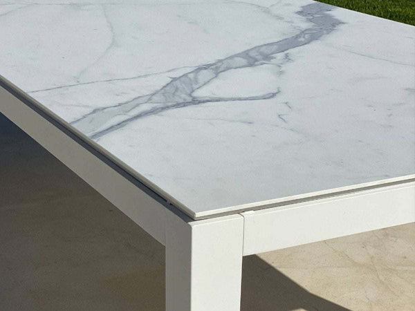 Dante Outdoor Ceramic Dining Table with charcoal frame and marble ceramic top on patio