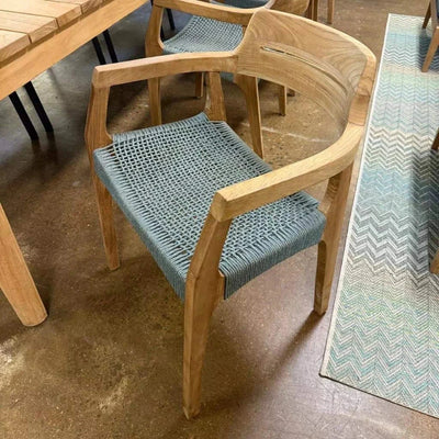 Jordan Outdoor Teak Dining Chair with curved teak frame and handwoven seat on patio.