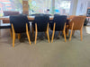Kai Leather Dining Chair in black and tan with timber legs around a dining table in a modern interior setting.