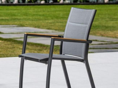 Marbella Outdoor Sling Dining Chair with aluminum frame, quick-dry sling, and teak armrests on a patio.