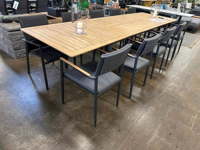 Milan Outdoor Teak Extendable Dining Table with chairs in a showroom setting.