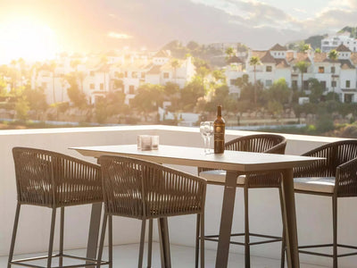 Jiselle Outdoor Bar Chair with Italian rope weaving and Sunbrella cushions on balcony at sunset.