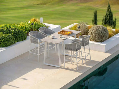 Jiselle Outdoor Bar Chair with Sunbrella cushions by a poolside table, featuring white frame with grey rope weaving, set in an elegant outdoor space.