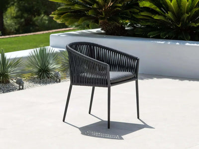 Outdoor setting with Jiselle Outdoor Rope Dining Chair featuring black rope weaving and charcoal aluminum frame.