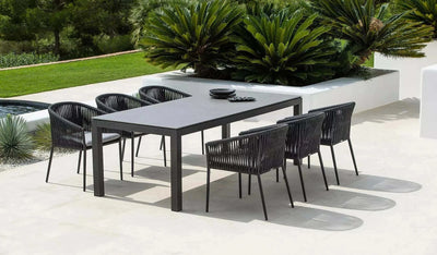 Jiselle Outdoor Rope Dining Chairs with charcoal aluminum frame and black rope around a sleek dining table in a garden setting.