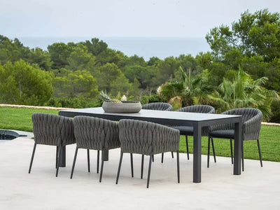 Dante Outdoor Ceramic Dining Table set in scenic garden, featuring durable aluminum frame and elegant ceramic top.