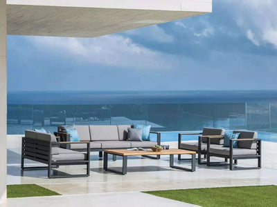 Belvedere Outdoor Lounge 2 Seater Sofa on patio with ocean view, featuring aluminum frame and teak trims.