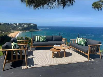 Finley Outdoor Lounge - 3 Seater Sofa with teak frame and Sunbrella cushions on a deck overlooking the ocean.