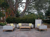 Manhattan Outdoor Lounge - 3 Seater Outdoor Sofa with teak wood base and handwoven wicker, featuring Sunbrella fabric cushions, in an elegant garden setting.