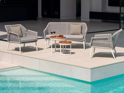 Outdoor seating area with two Bertus Outdoor Ceramic Coffee Tables, featuring a modern design with durable aluminum frames and round ceramic tabletops, set by a poolside.