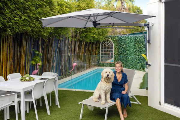 Retreat wall-mounted outdoor umbrella shading poolside seating area with woman and dog