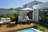 Retreat wall-mounted outdoor umbrella shading loungers on wooden deck by modern house and pool
