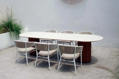 Toledo Ceramic Outdoor Dining Table with oval ceramic top and solid teak bases in modern outdoor setting