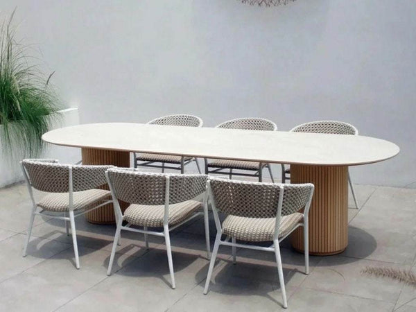 Toledo Ceramic Outdoor Dining Table with oval ceramic top and solid teak cylindrical bases in modern patio setting